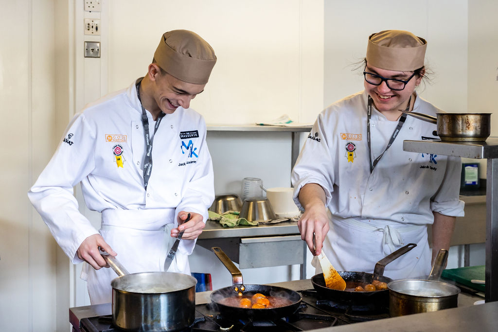two student chefs frying food