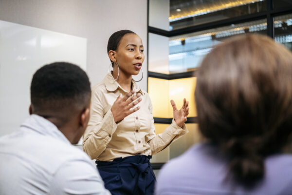 Passionate young woman in her 20s with short hair, discussing with colleagues, African female manger leading her team, ambition, aspiration, empowerment