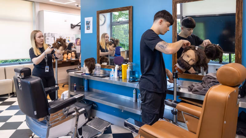Barbering students styling hair in the college salon.