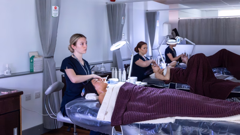 Beauty therapy students providing facial treatments in a salon environment.