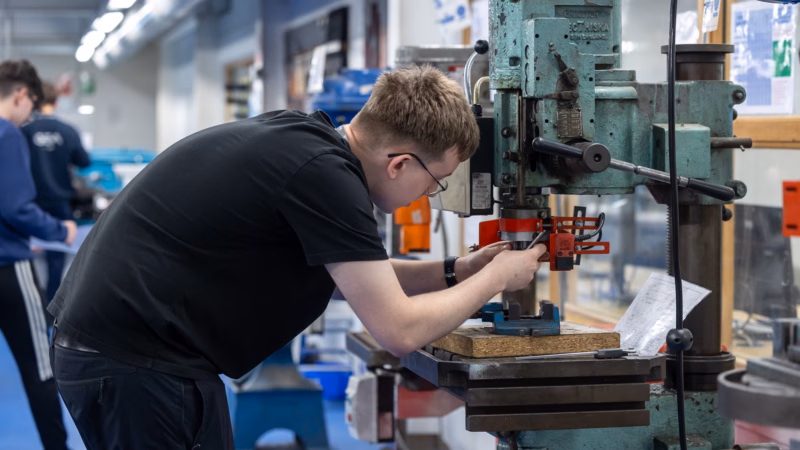 Engineering students operating precision machinery in the workshop.