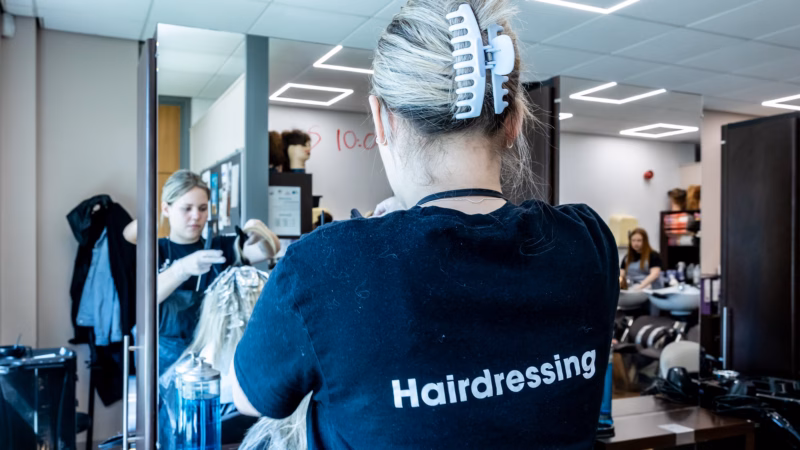 Hairdressing students styling hair in the college salon.