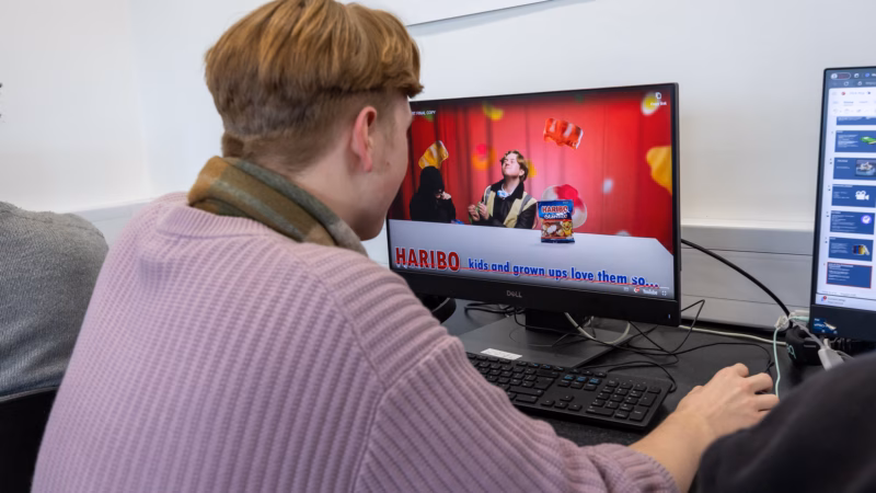 Creative media students editing videos and graphics on desktop software.