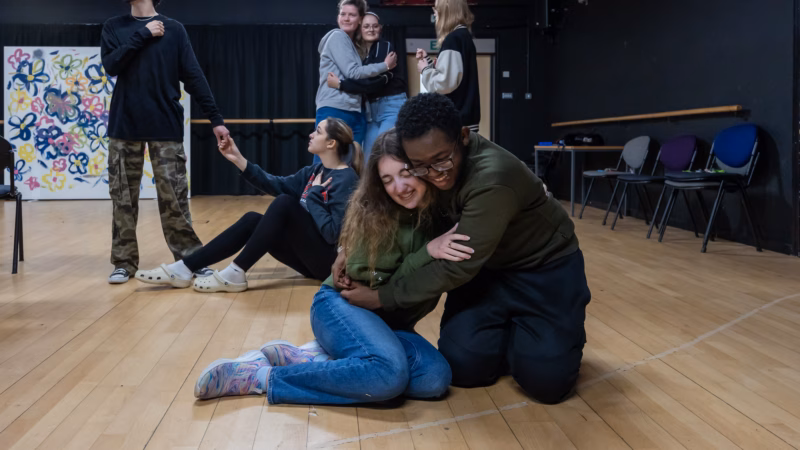 Performing arts students rehearsing a drama scene on stage.