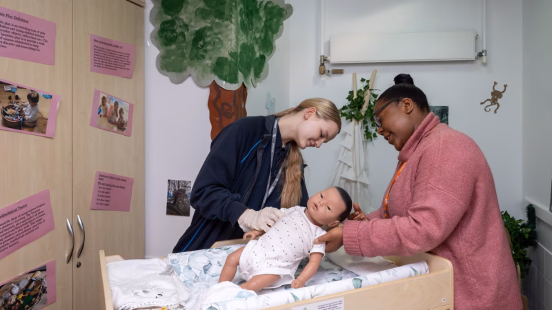 Care students practising infant care with a training doll.