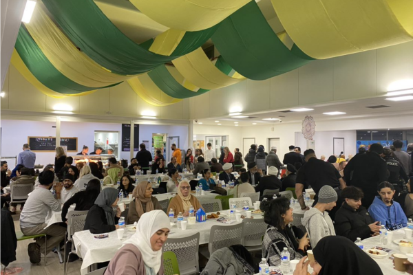 Guests sit down underneath green and yellow banners for a Community Iftar event to mark Ramadan.