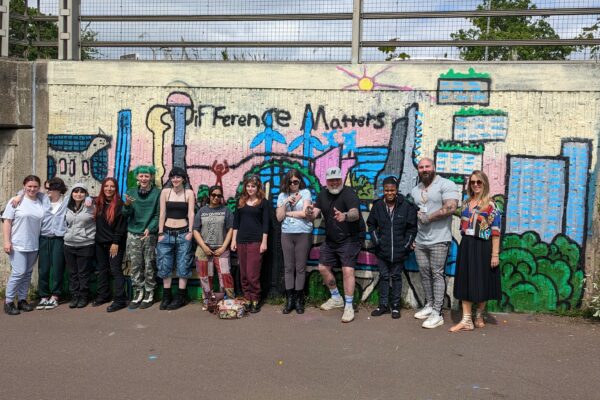 A group of Art & Design students from Milton Keynes College working with Mr Meana to spray paint a mural in a Bletchley walkway.