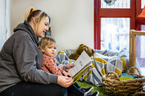 Childcare student reading a kids book to a child who is sat in her lap