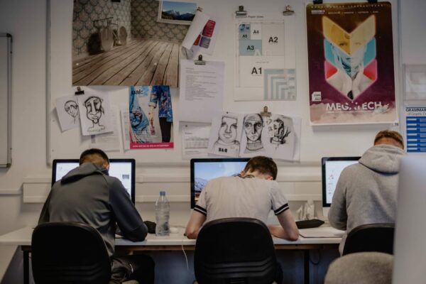 3 male graphic design students sat a computers