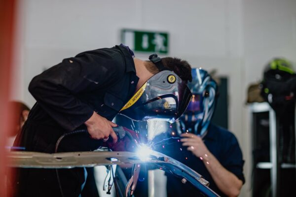 Motor vehicle student welding metal parts together