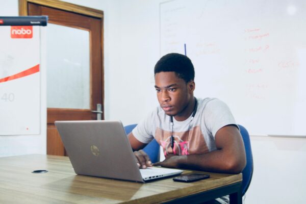 Male student sat in a classroom working on his laptop
