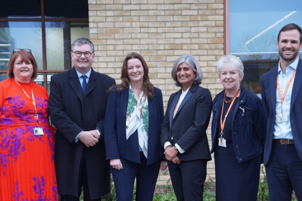 Gillian Keegan (centre left) pictured with Iain Stewart MP (second from left) stood in a line with senior leaders from Milton Keynes College Group. Everyone is dressed in smart clothes, and they are stood outside the South Central Institute of Technology building in Bletchley.