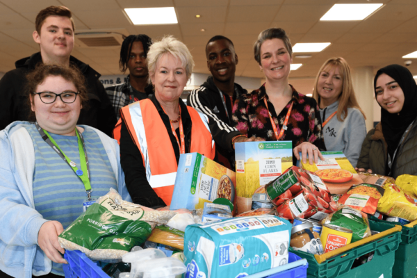 Students and staff from Milton Keynes College standing in front of baskets of food donations.