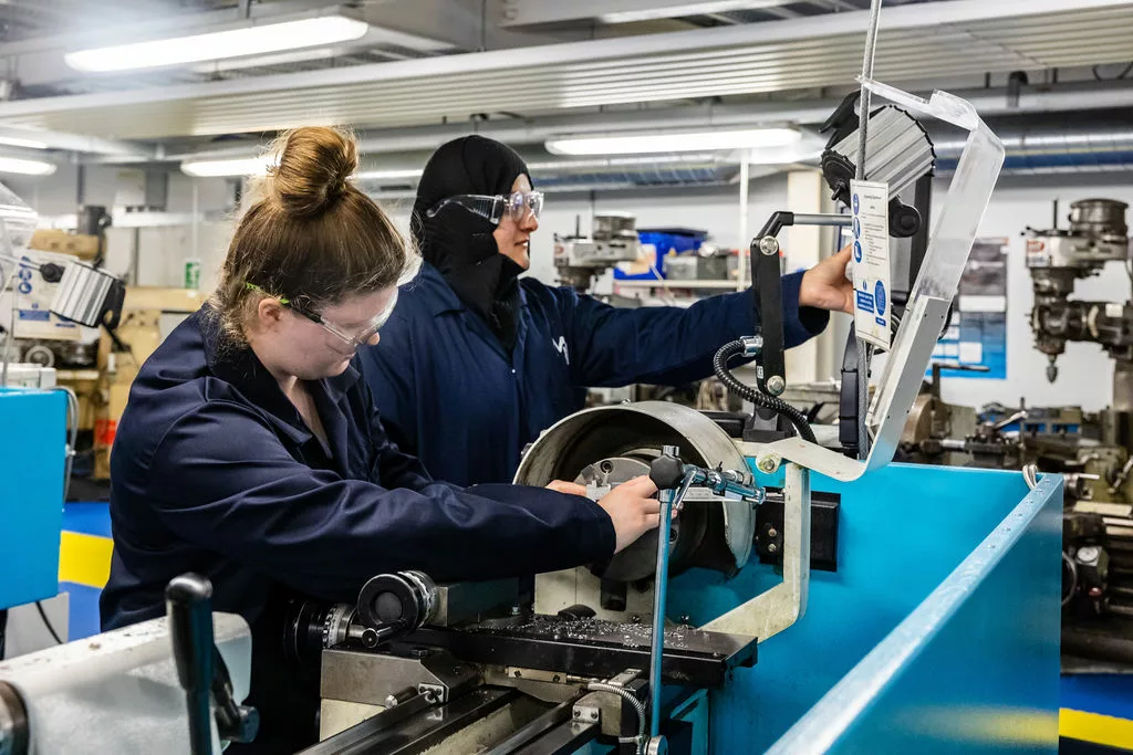 Engineering students in the workshop using metal machines