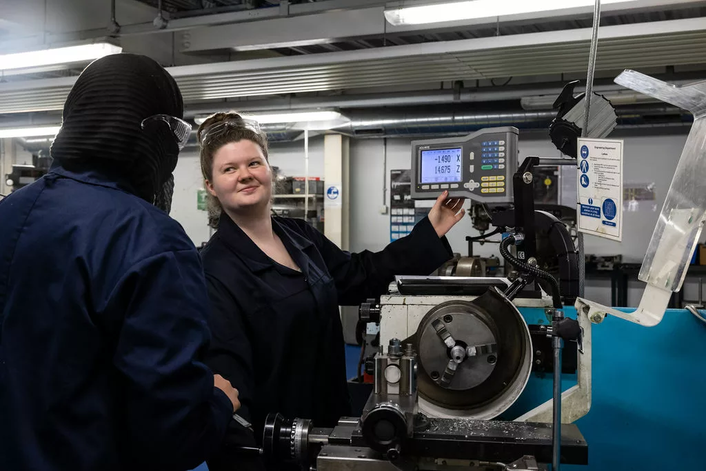 Engineering students in the workshop using metal machines