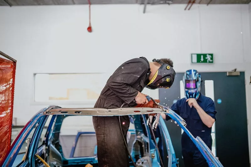 Motor vehicle students working on a car welding parts together