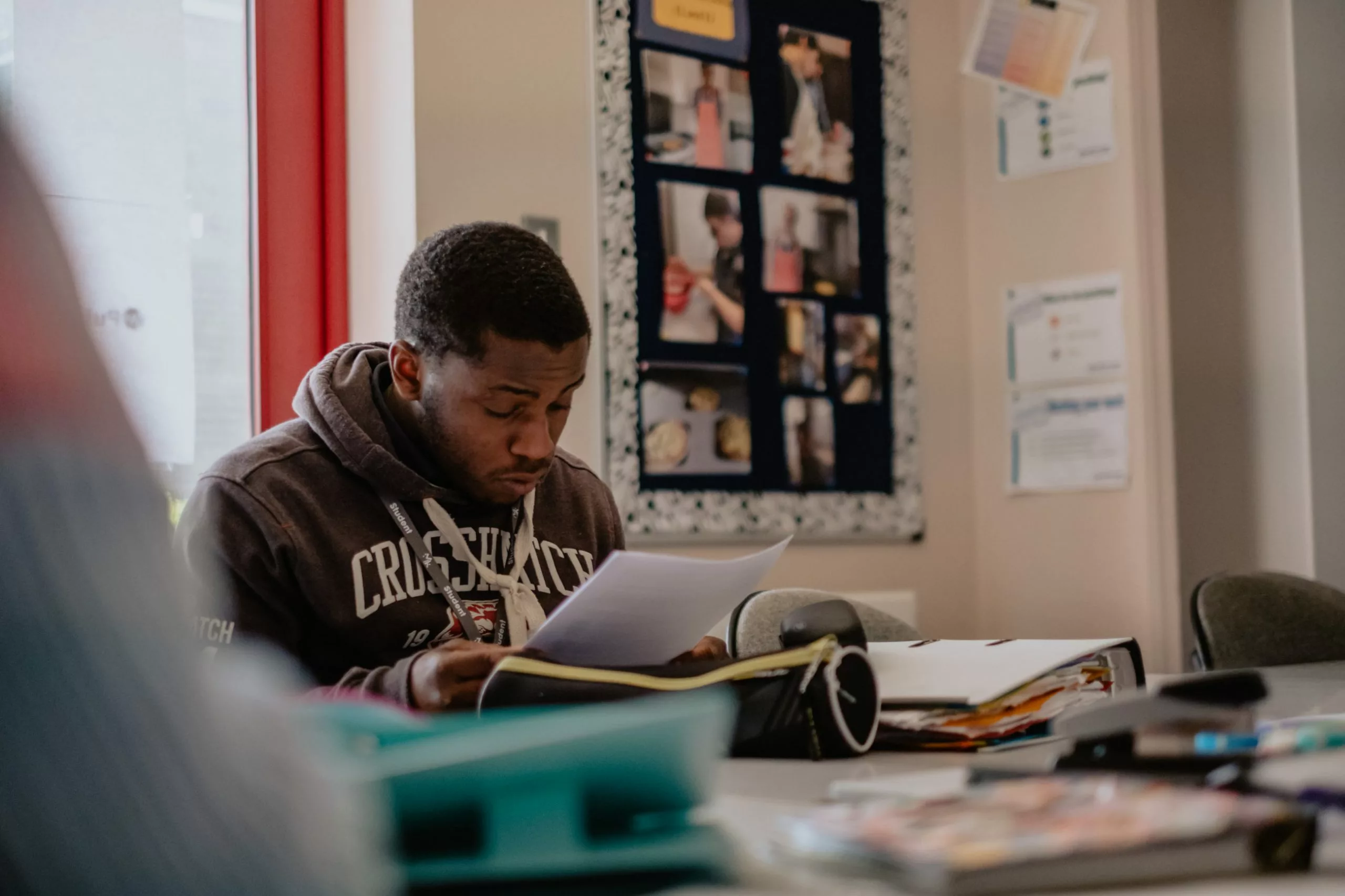 A male student sat at a desk looking at a piece of paper