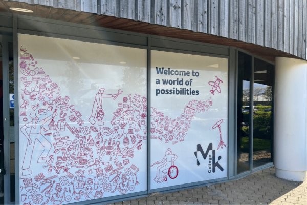 A mural designd by a former student on the front door of the Milton Keynes College Chaffron Way campus. The mural has lots of small pink icons themed around college life, with the caption of 'Welcome to a world of possibilities' next to it.