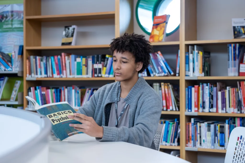 A student reading a book in a library, focused on their studies.