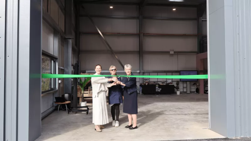 Emily Darlington MP, Milton Keynes Mayor Marie Bradburn and CEO of MK College Group Sally Alexander at the opening of the College Group's new Green Skills Centre. Emily, Marie and Sally are stood in a large doorway with a green ribbon across it and they are about to cut the ribbon with a pair of gold scissors.