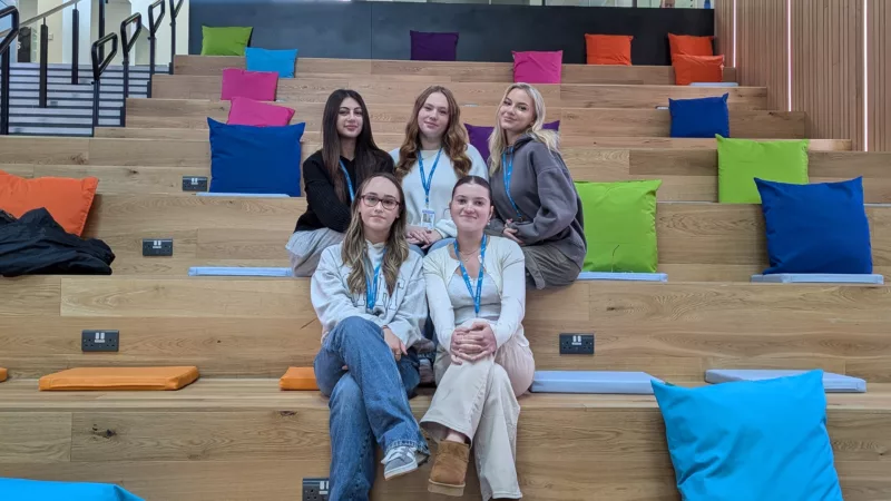 Five A Level students from MK College. The students are sat in two rows on benches at the South Central Institute of Technology.