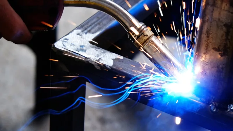 Welding tool being used, pictured with a blue flame and sparks.