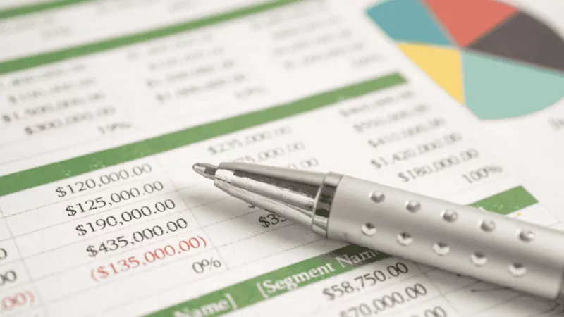 A close-up of a financial spreadsheet with a pen resting on top.