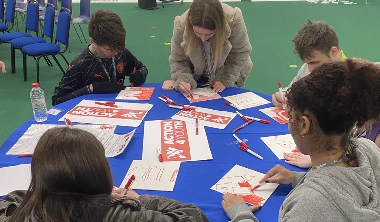 Students working on a project – A group of students collaborating at a table with art and craft supplies.