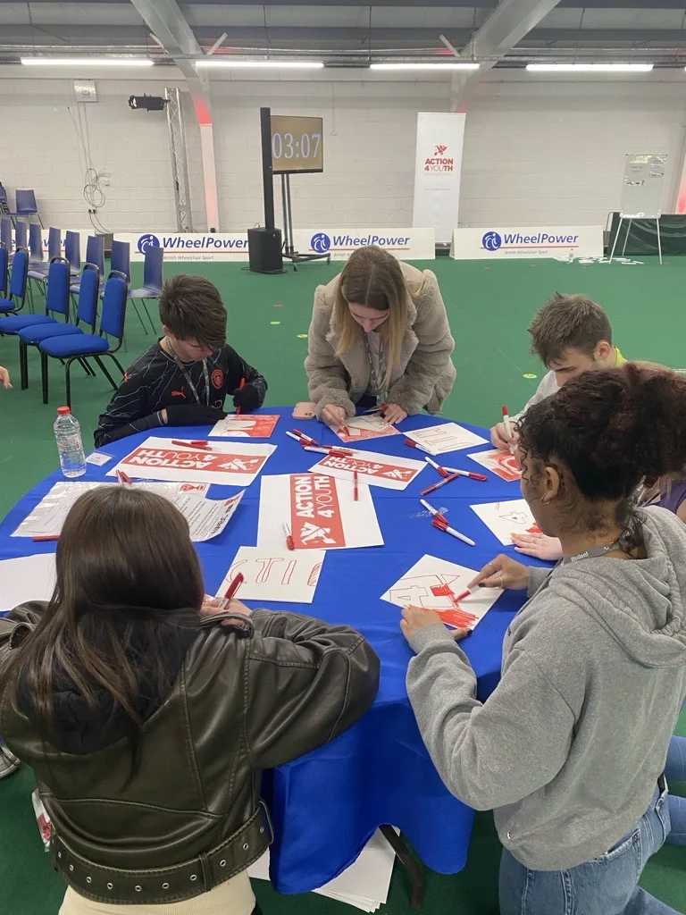 Students working on a project – A group of students collaborating at a table with art and craft supplies.