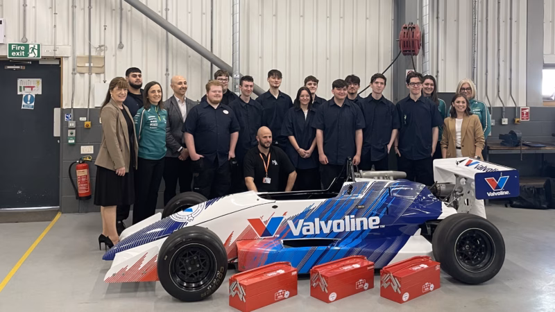 Staff from Aston Martin’s Aramco Formula® One Team, Valvoline Global Operations and MK College pictured with Motor Vehicle students from MK College. Everyone is stood behind a racing car that the students have been working on as part of the project.