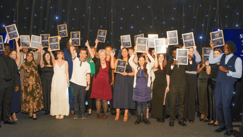 All of the Students of the Year Award winners on stage holding their certificates above their heads.