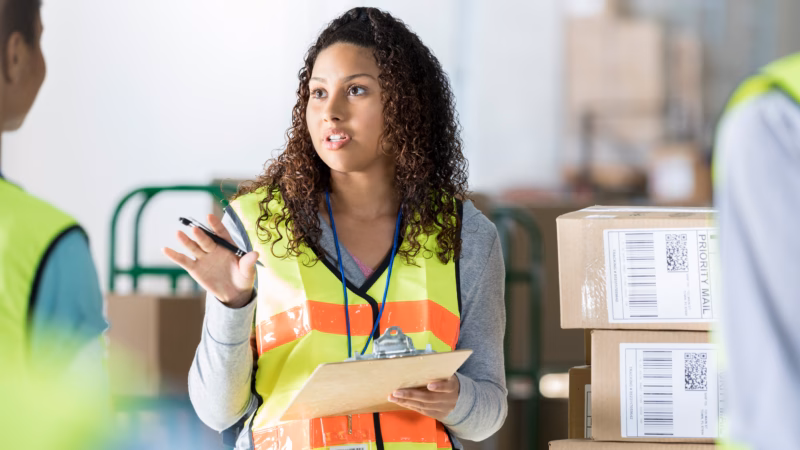 Woman working in warehouse with clipboard